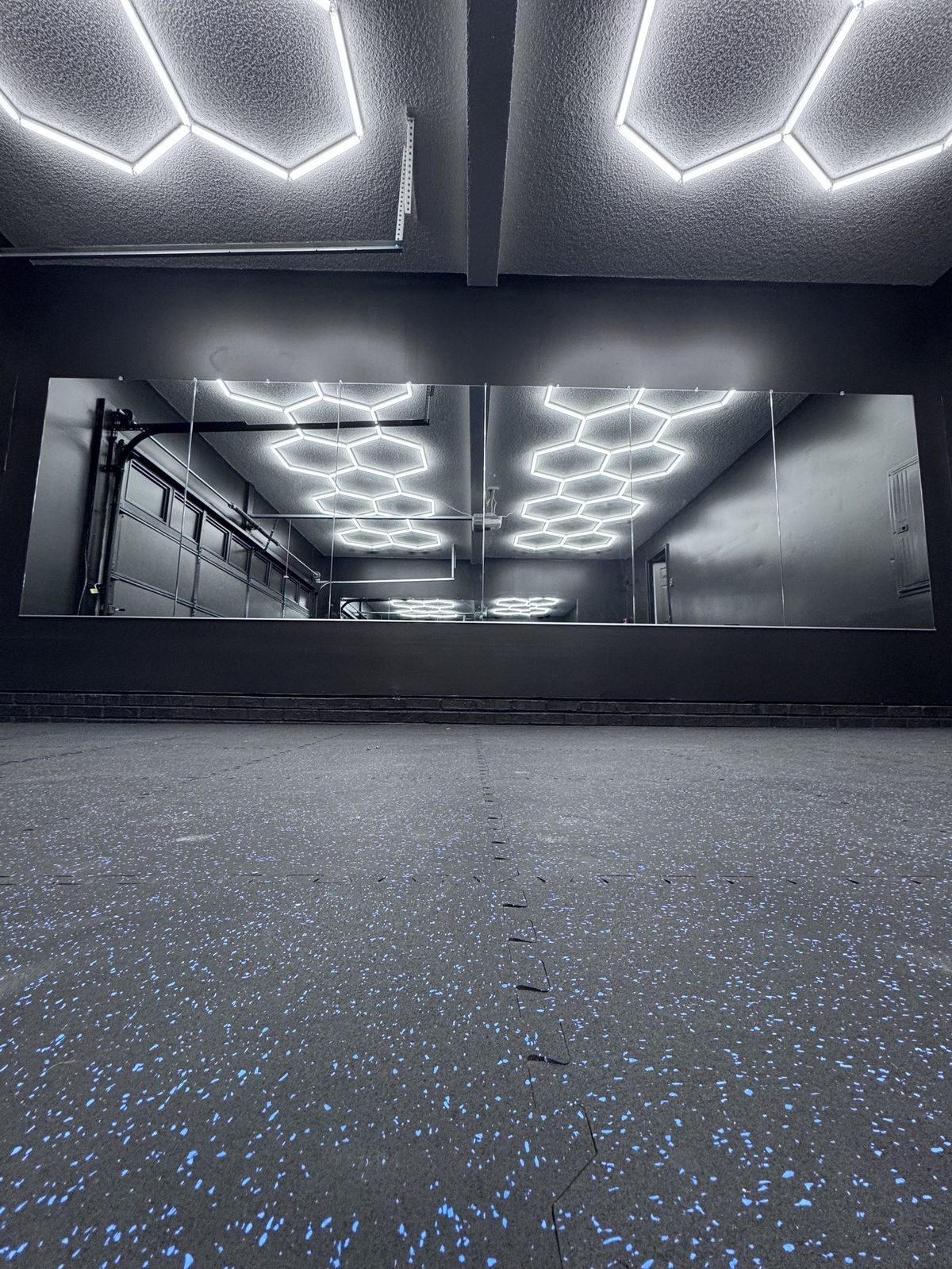 Mirror wall installed in a commercial gym with hexagon lighting